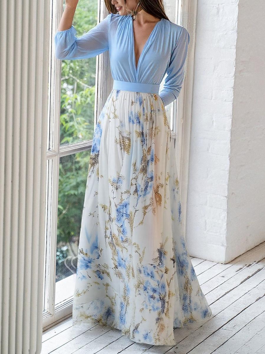 Woman styled in a flowing floral maxi dress with a fitted waist on a plain background.