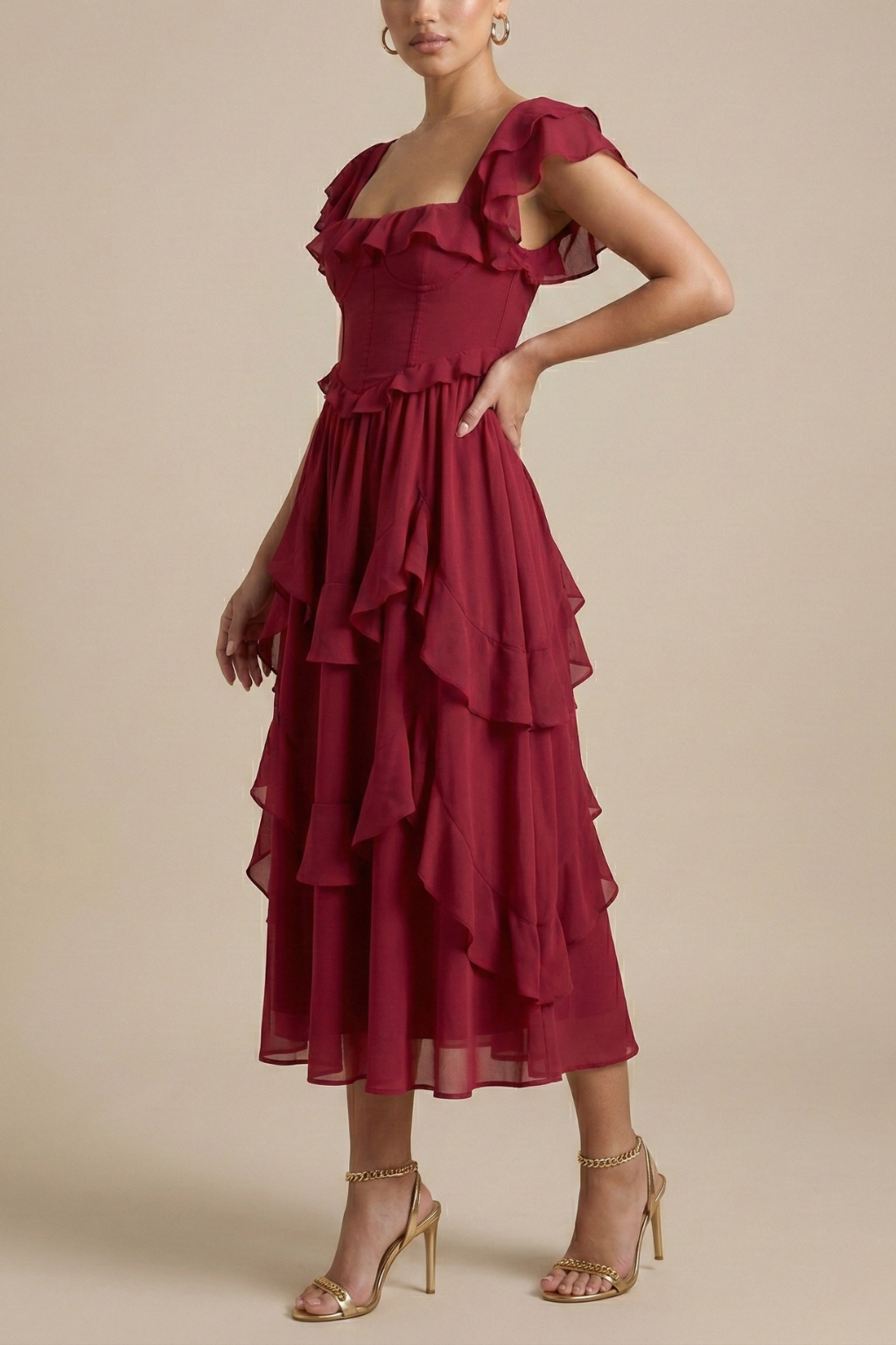 Female model in a flutter sleeve midi dress with soft layered ruffles on a plain background.
