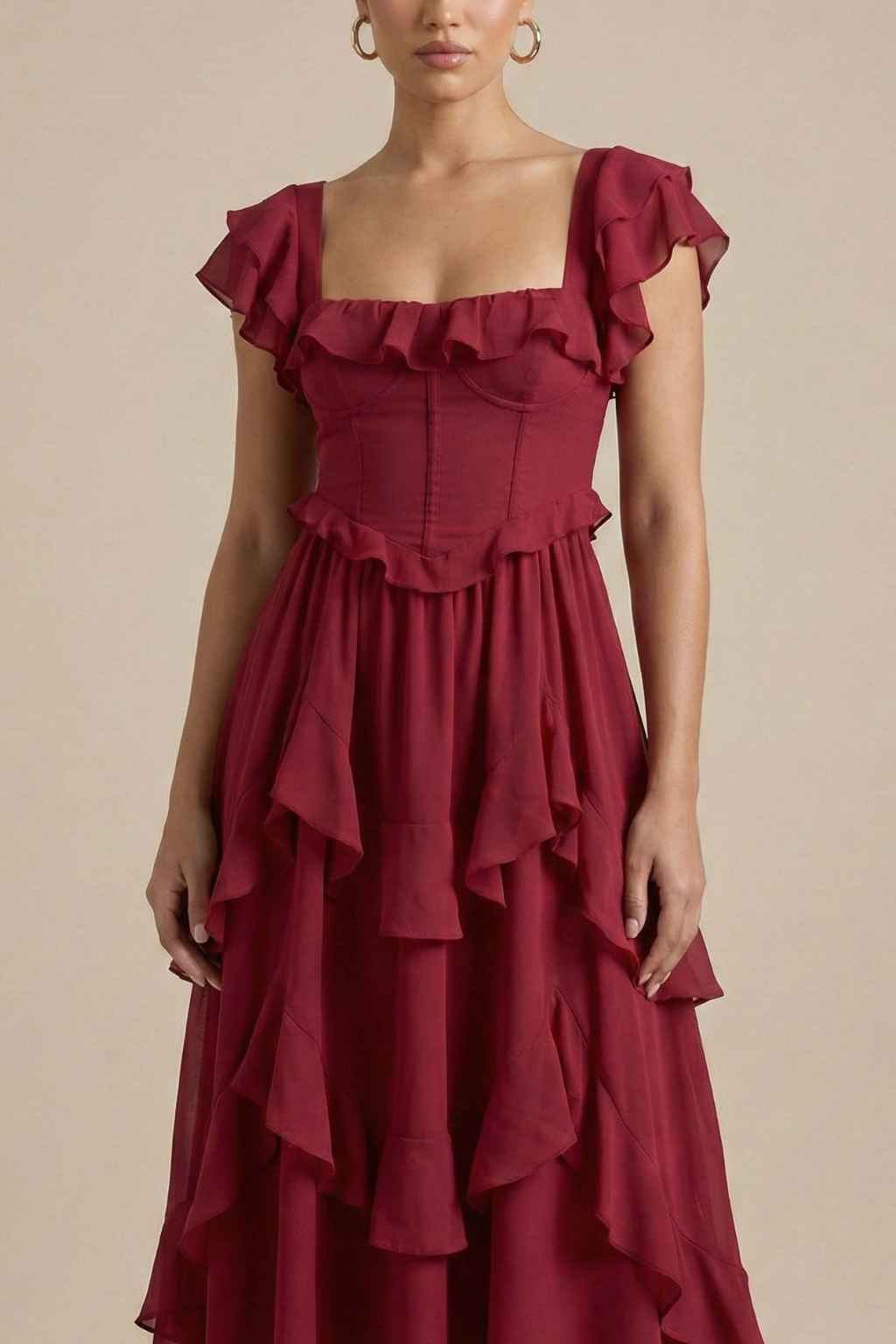 Woman showcasing a fitted waist midi dress with cascading skirt panels on a plain background.