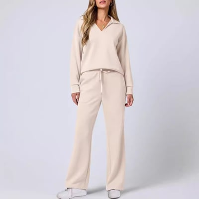 Woman wearing a fitted jogging suit set with leggings against a plain background.
