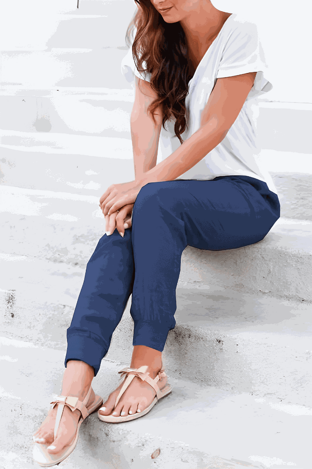 Woman showcasing relaxed ankle pants with a streamlined silhouette on a plain background.
