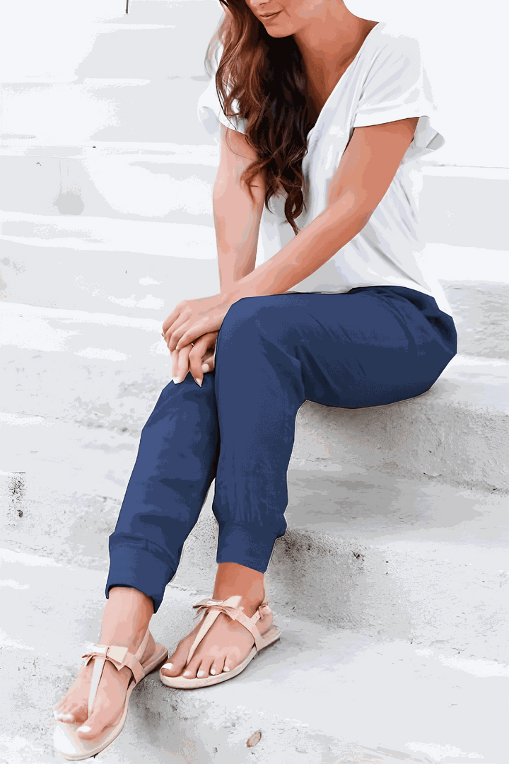 Woman showcasing relaxed ankle pants with a streamlined silhouette on a plain background.
