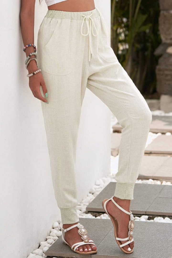 Female model showcasing casual drawstring trousers with a tapered leg silhouette.
