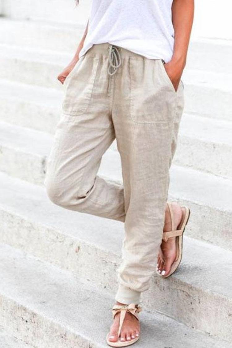 Woman wearing lightweight ankle pants with gathered cuffs against a plain background.
