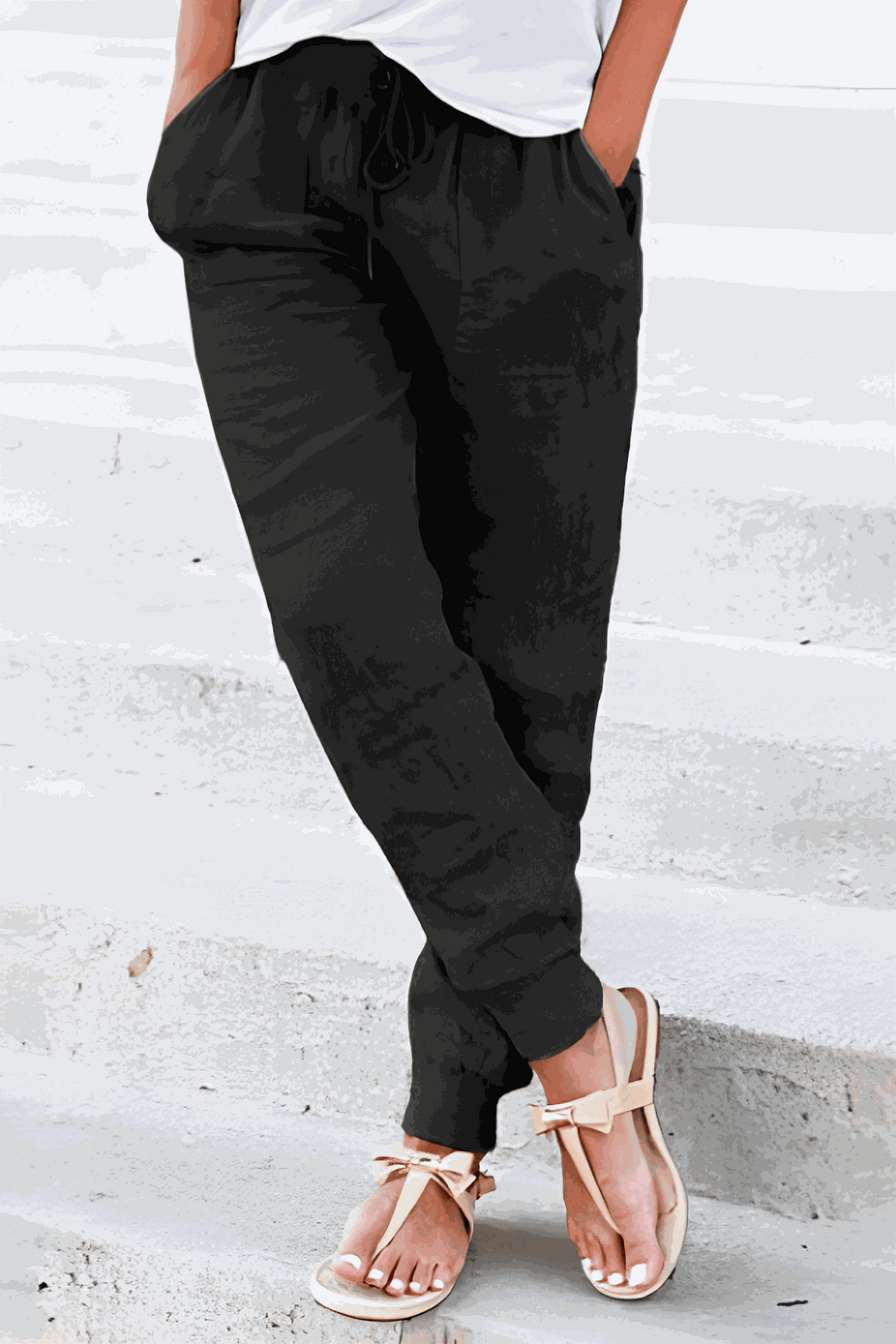 Female model in casual trousers featuring side pockets and an adjustable waistband.
