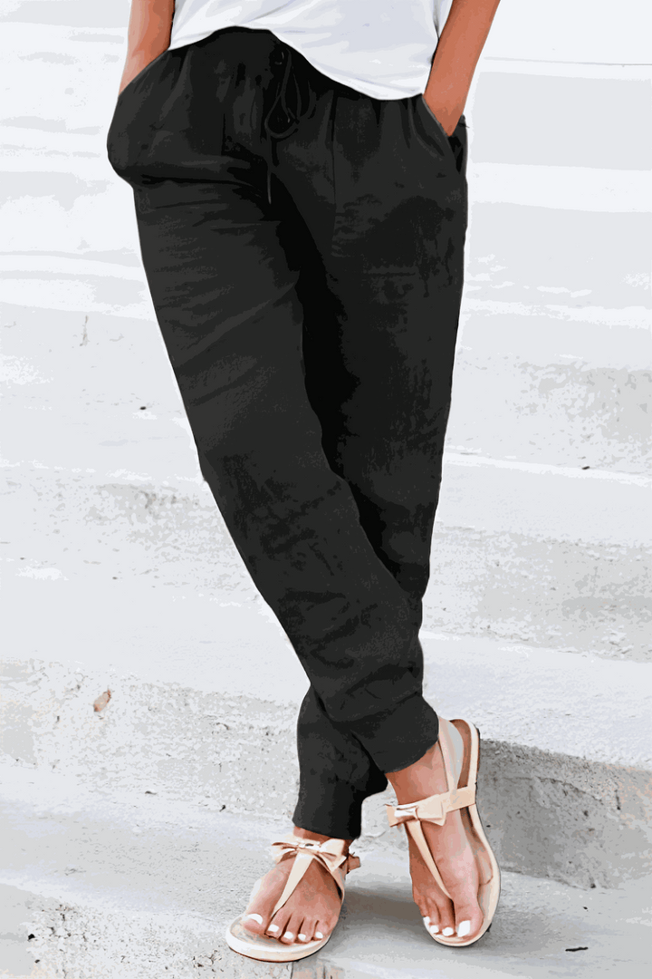 Female model in casual trousers featuring side pockets and an adjustable waistband.
