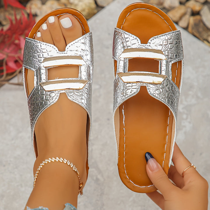 Woman wearing casual slide sandals with buckle detail on a plain background.