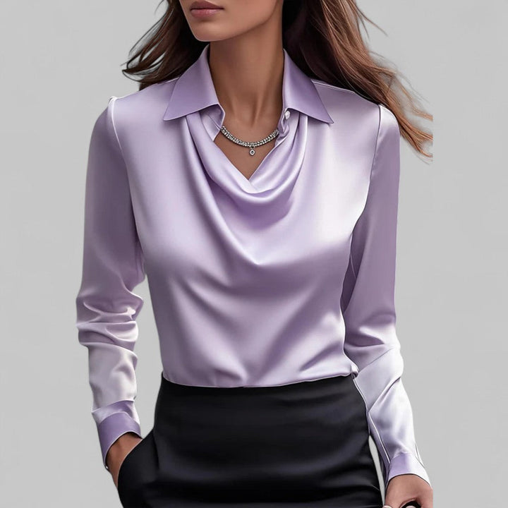  Woman wearing a satin blouse with a soft neckline and tailored fit against a plain backdrop.