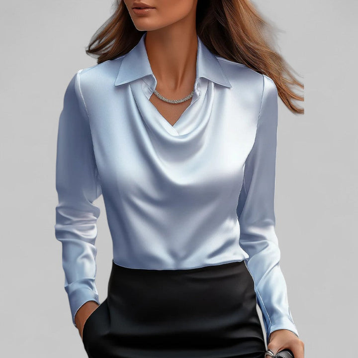 Female model wearing a long sleeve blouse with a draped neckline against a plain background.