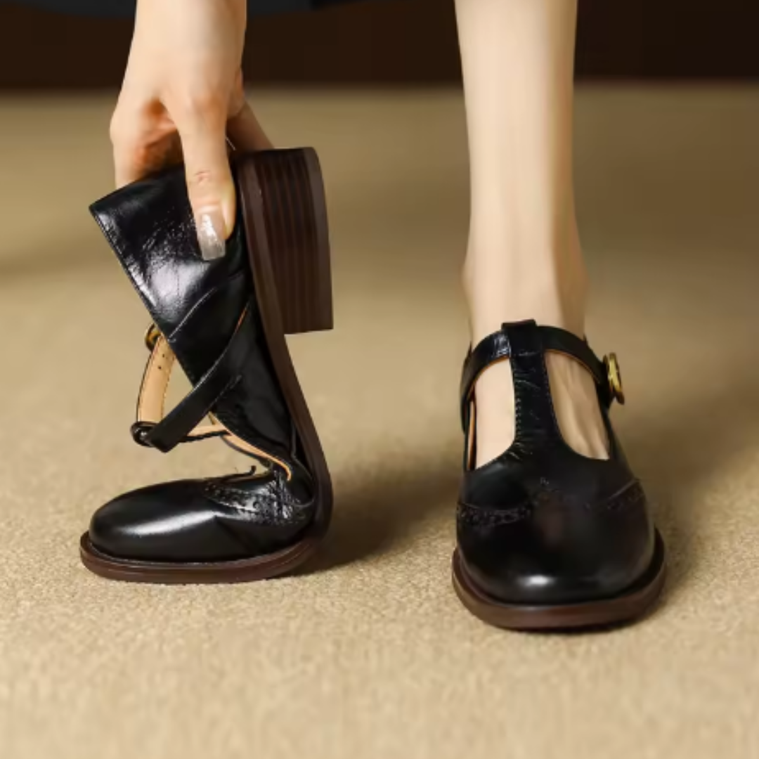 Polished Mary Jane shoe with wingtip styling on a plain background.