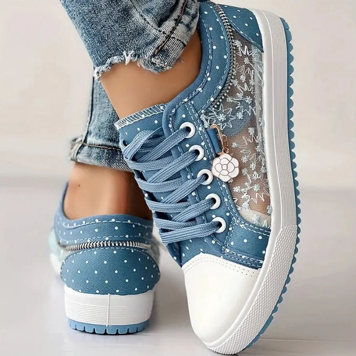  Female model wearing everyday lace-up trainers on a plain background.