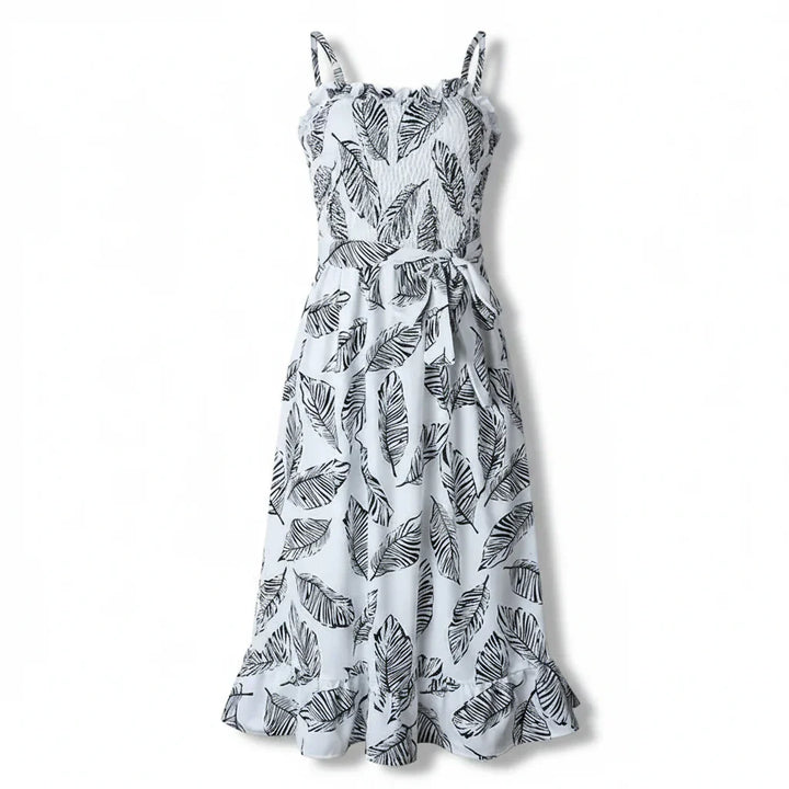 Flowy midi dress with leaf print and tie waist against a plain background.