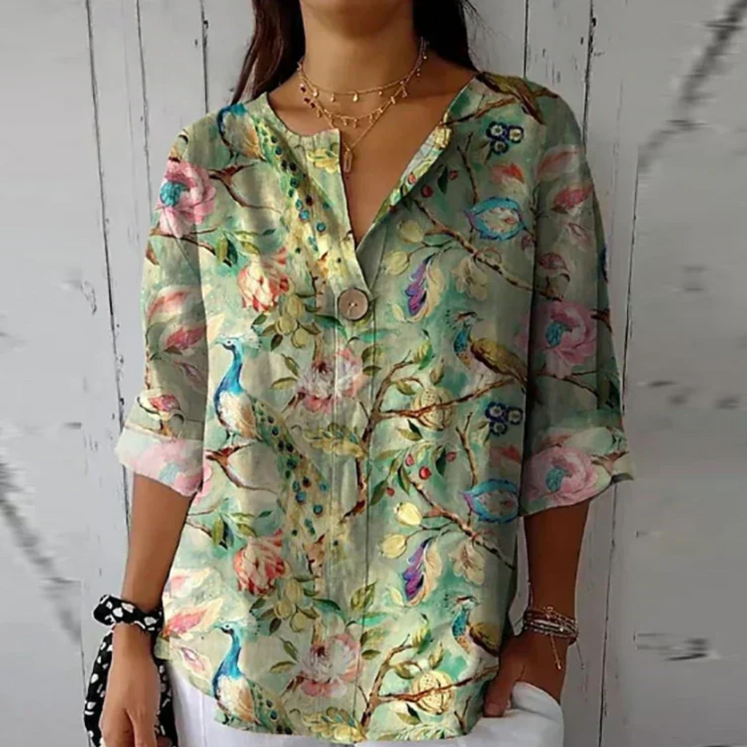 Woman wearing a casual floral blouse with long sleeves.