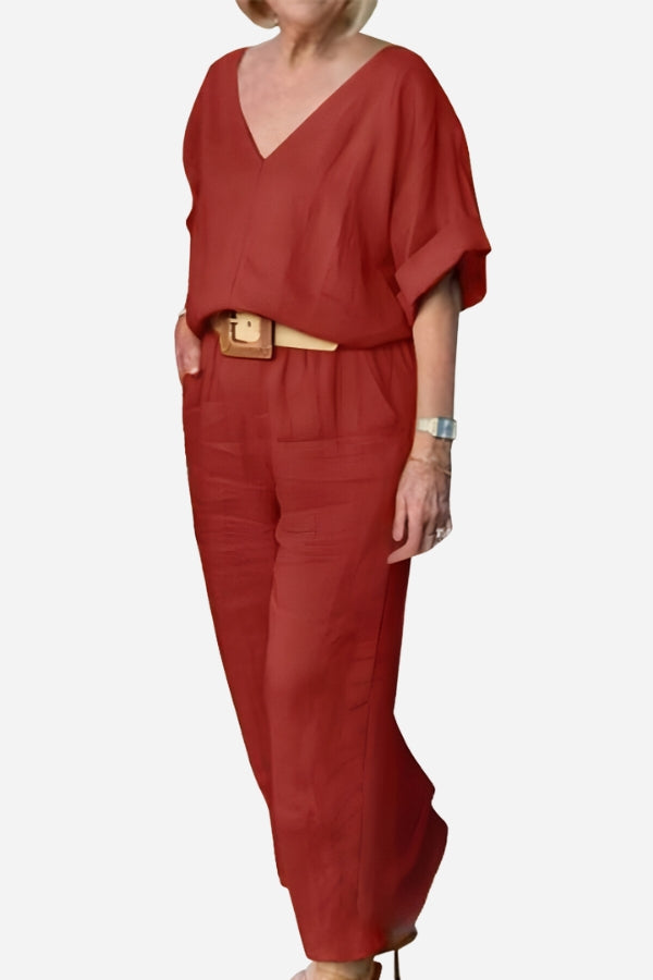 Female model wearing a two-piece outfit with a V-neck top and straight-leg trousers on a plain background.