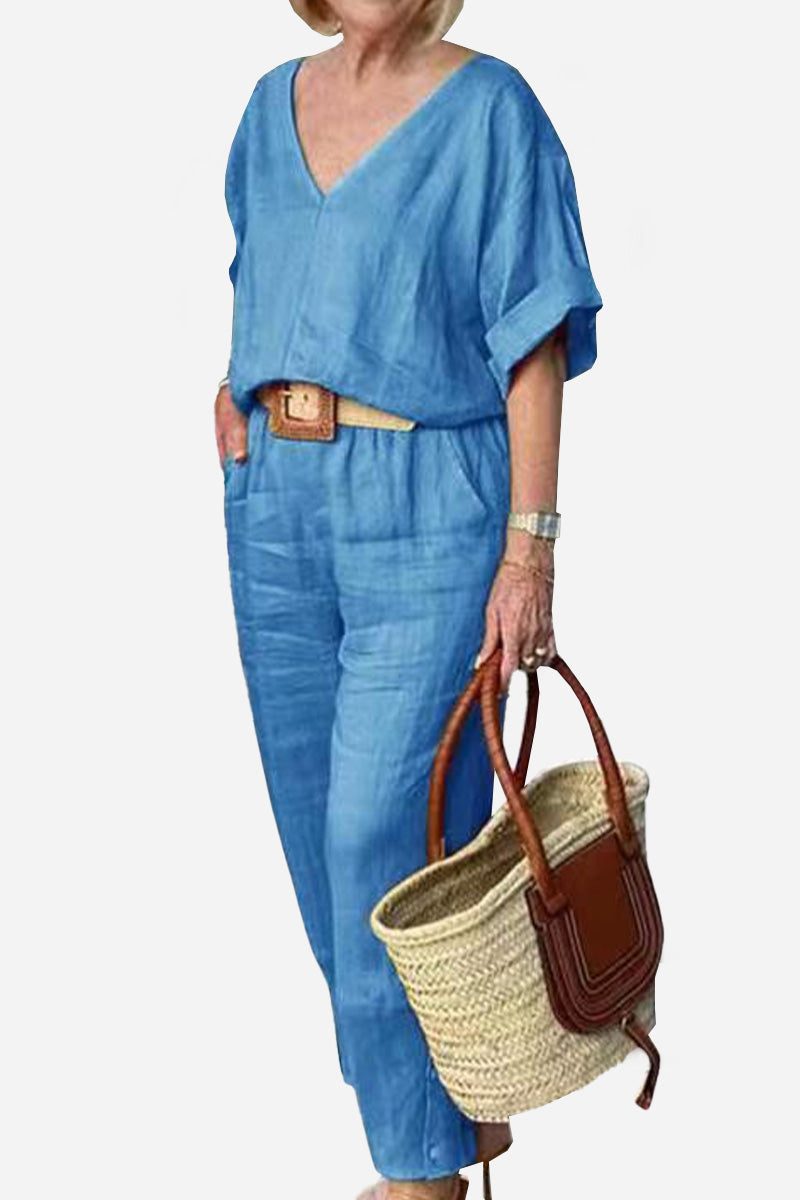 Woman wearing a matching outfit with a V-neck top and straight-leg trousers against a plain backdrop.
