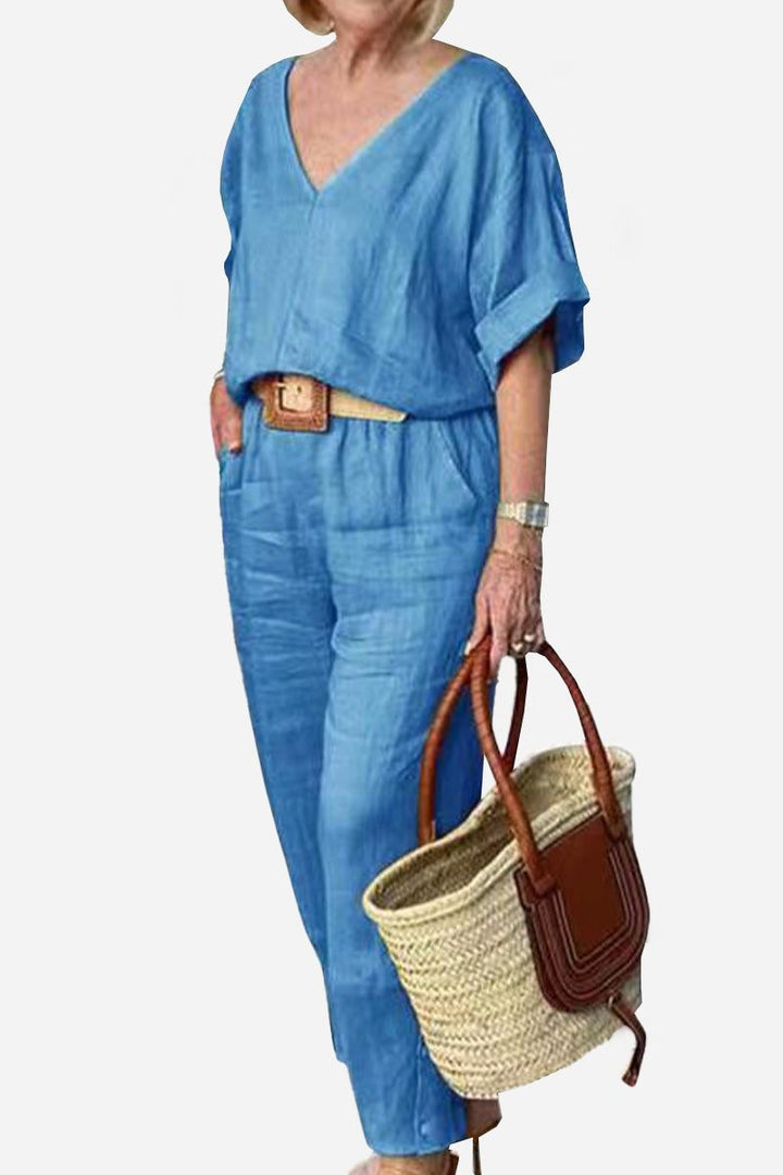 Woman wearing a matching outfit with a V-neck top and straight-leg trousers against a plain backdrop.