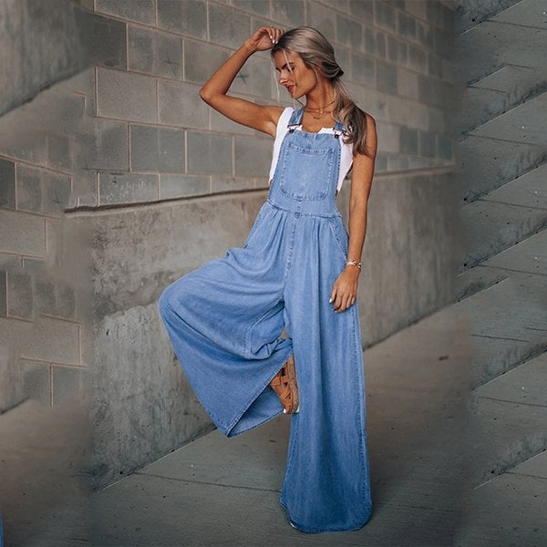 Woman in a wide-leg denim jumpsuit standing against a plain background.