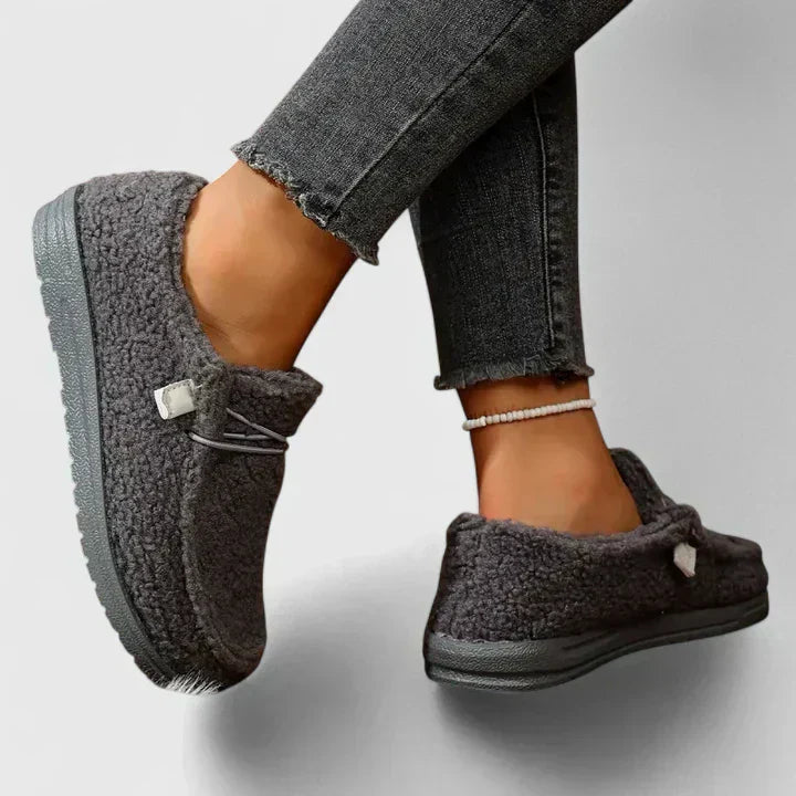 Woman styling classic loafers against a plain background.