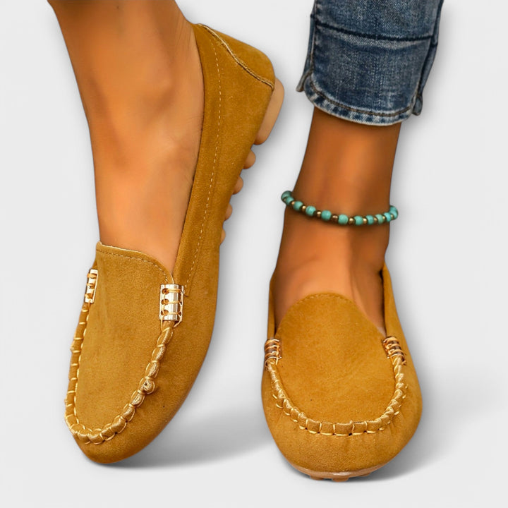Woman showcasing flexible moccasin slip-on shoes with classic stitching.