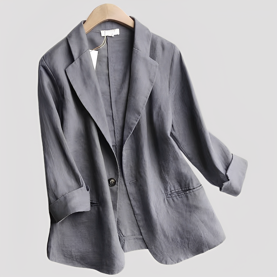 Woman showcasing a tailored blazer with three-quarter sleeves on a plain background.
