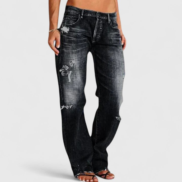 Woman showcasing wide-leg flare jeans with a fitted upper silhouette on a plain background.