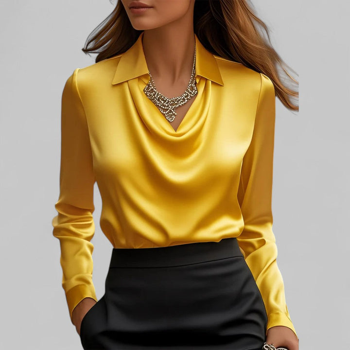  Woman showcasing an elegant long sleeve blouse with a softly draped front on a plain background.