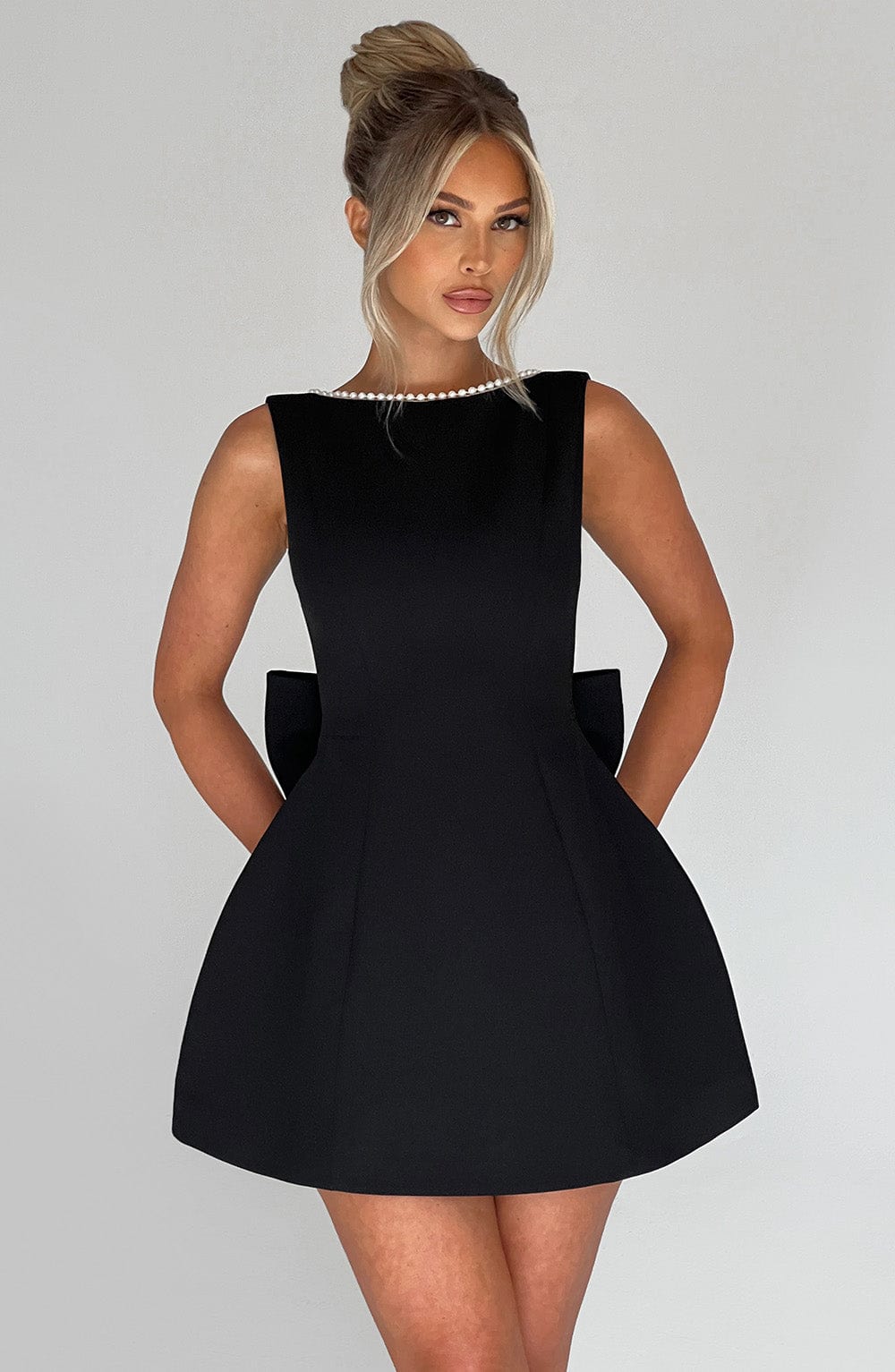  Female wearing an occasion dress with a defined waistline on a plain background.
