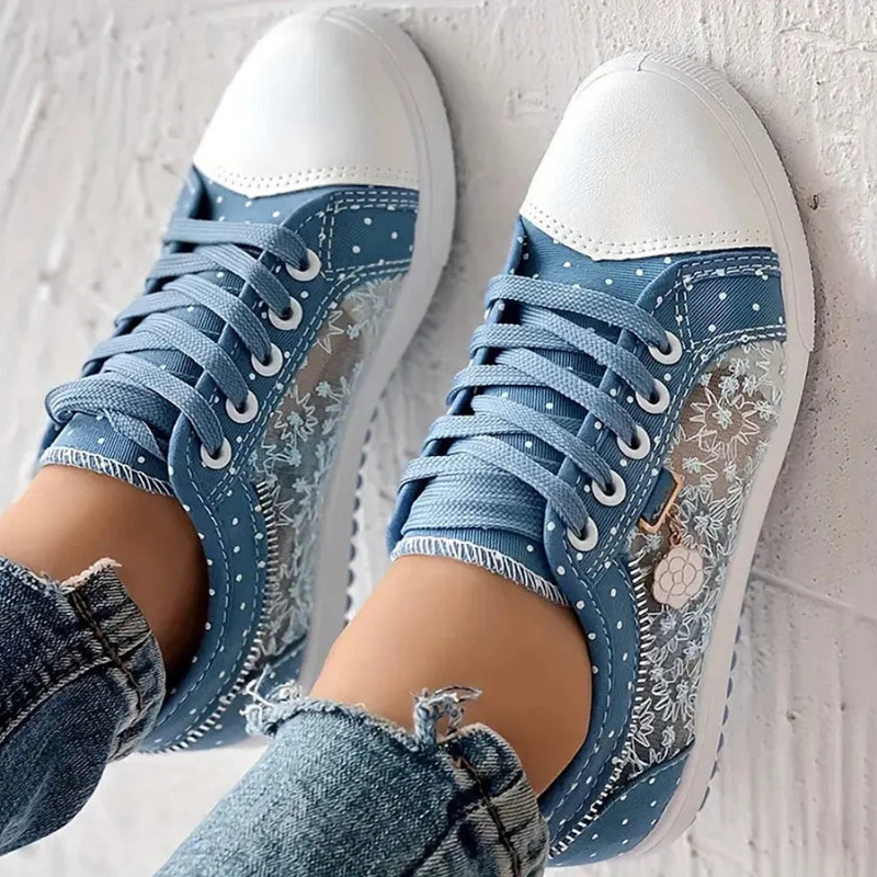  Woman displaying classic trainers with an adjustable lace-up fastening on a plain background.