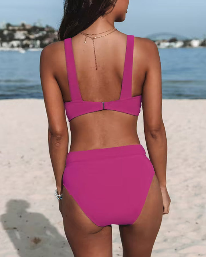 Woman showcasing a modern one-piece bathing suit on a plain background.