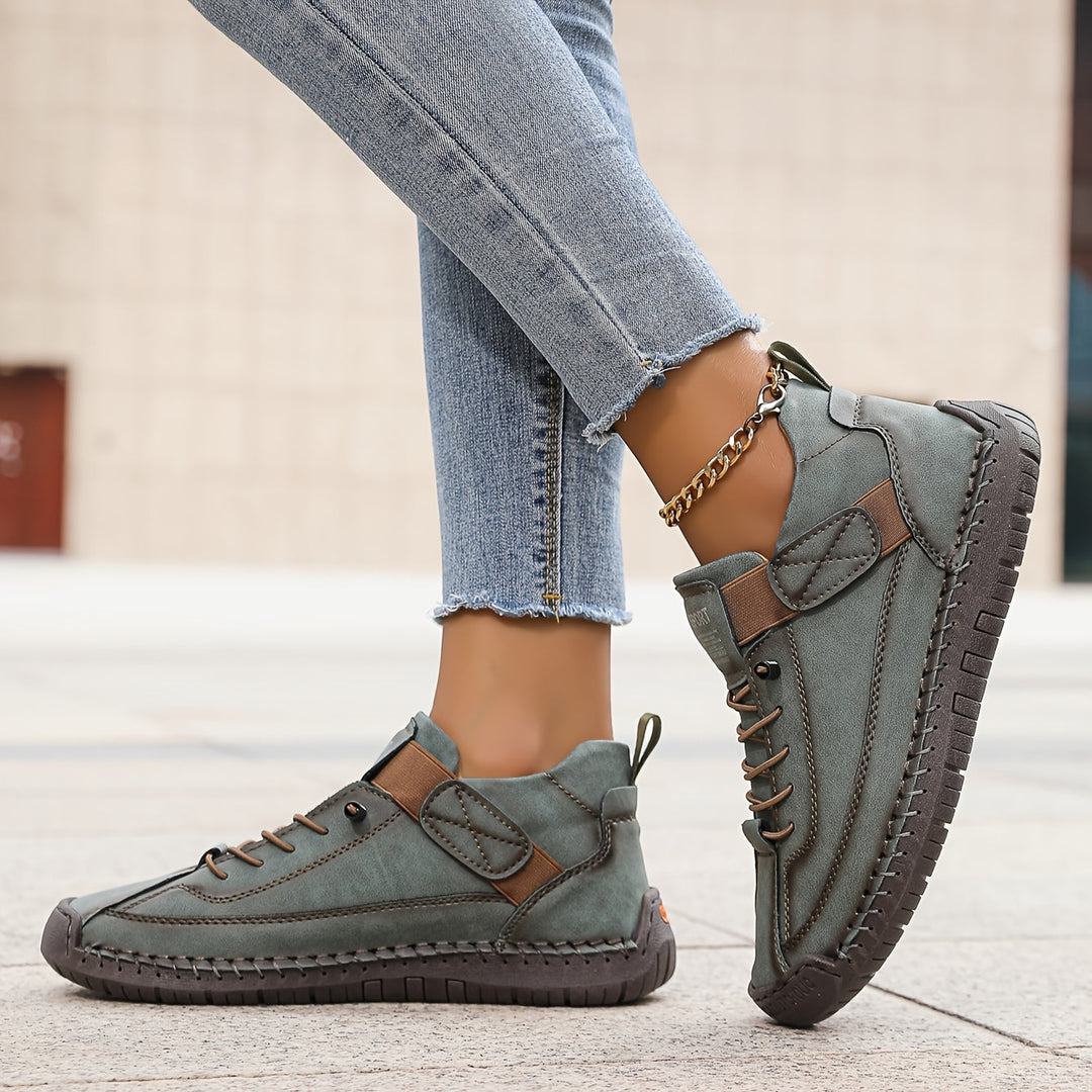 Female wearing lace-up walking trainers with a contemporary silhouette on a plain background.