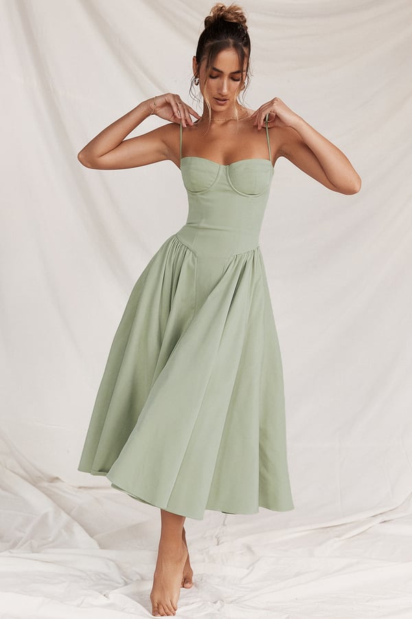 Woman wearing a flowing midi dress with slim straps on a plain background.