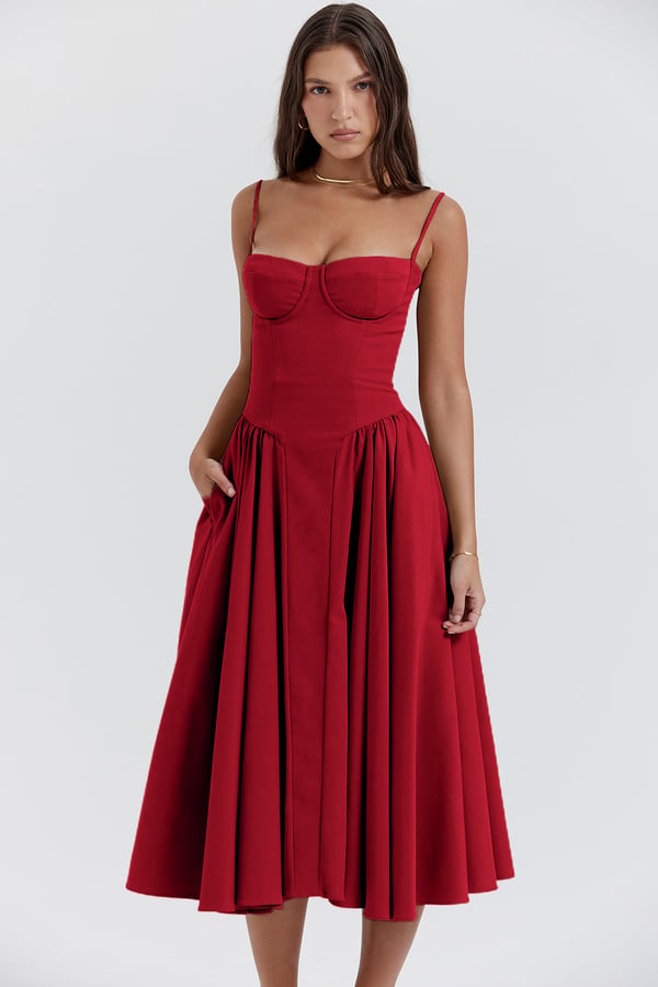 Female model showcasing a feminine midi dress with delicate straps on a plain background.
