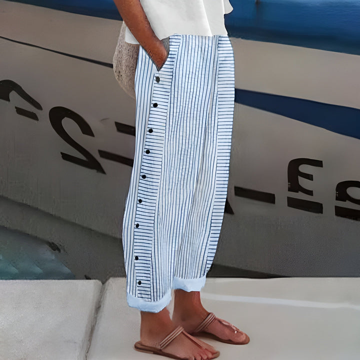 Woman wearing striped trousers with side pockets against a plain background.