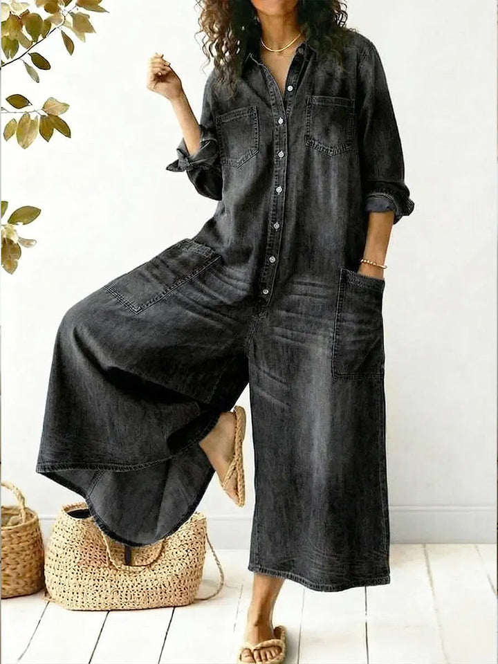 Woman styled in a casual denim jumpsuit with chest pockets on a plain background.