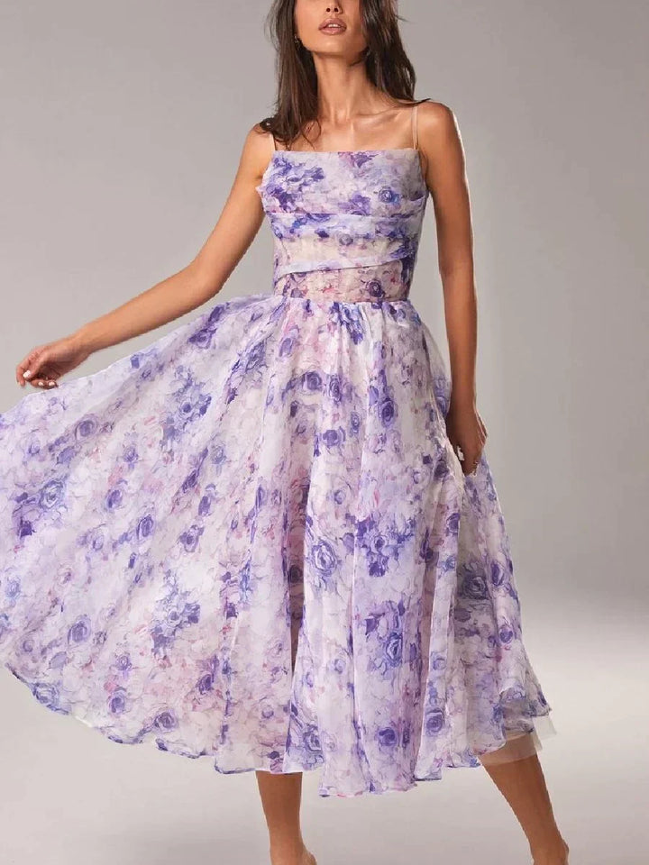  Woman in a sleeveless floral dress with a flowing midi-length skirt on a plain background.