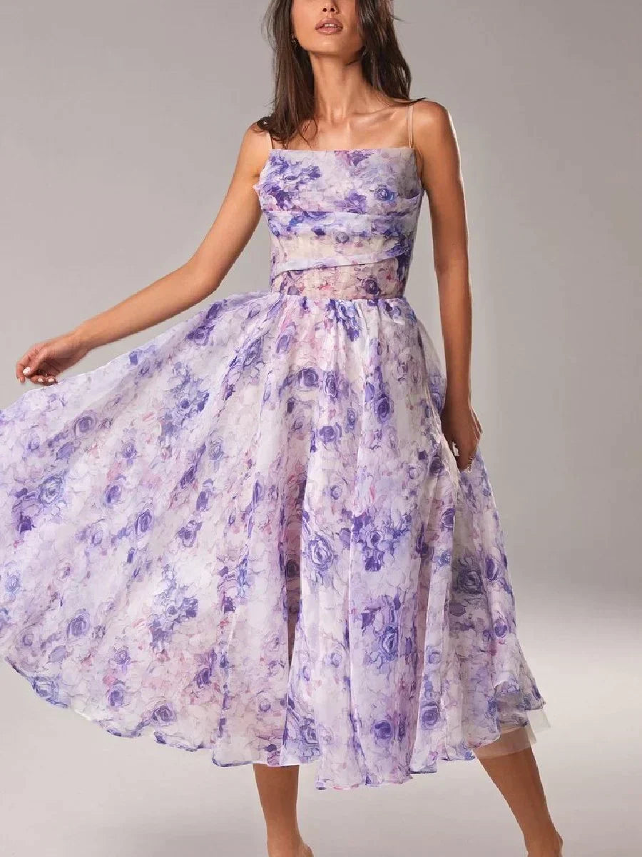 Female model in a floral print midi dress with a fitted bodice and flared skirt on a plain background.