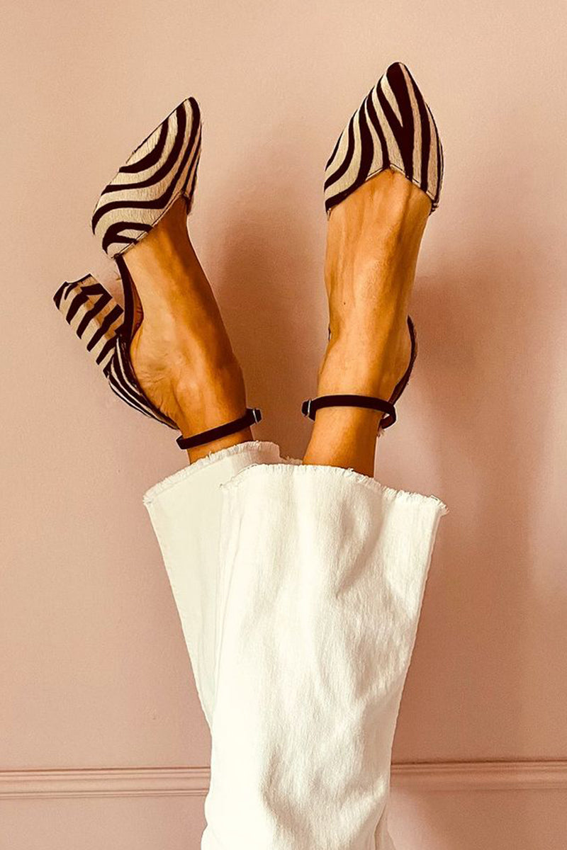 Woman wearing zebra print mid heel sandals against a plain background