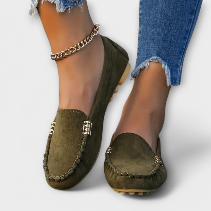 Female model wearing lightweight moccasin slip-ons on a plain background.