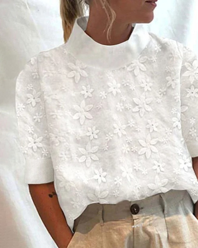 Female wearing a floral embroidered blouse with a stand collar against a plain background.