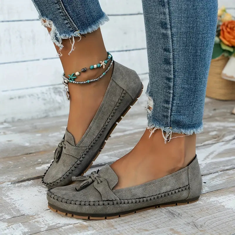 Elegant women’s loafers with decorative bow shown on a plain background.