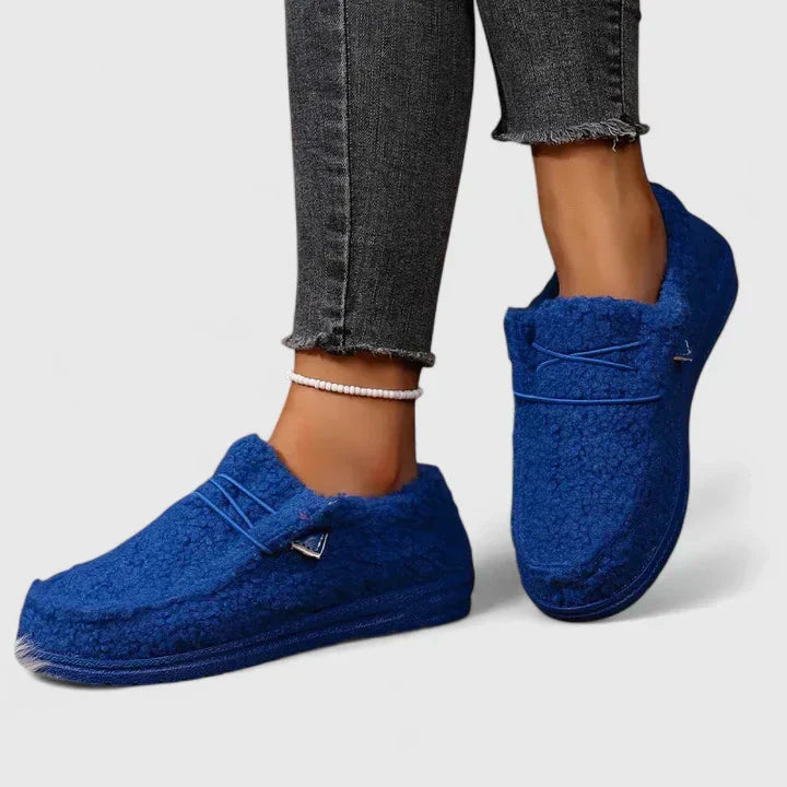 Woman standing in comfortable loafers with a plain background.