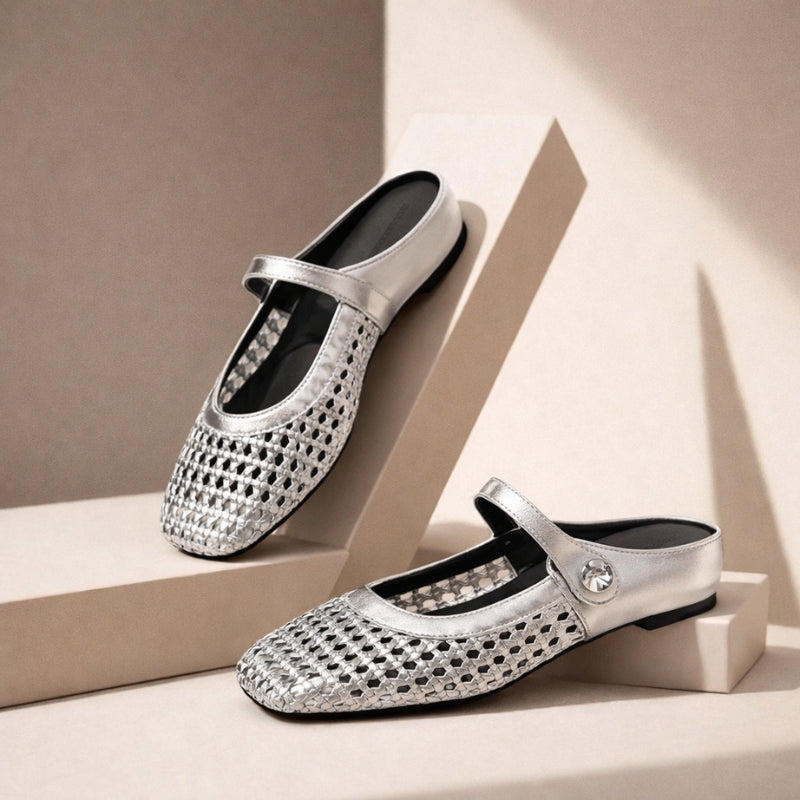 Woven metallic flat mules on a plain background.

