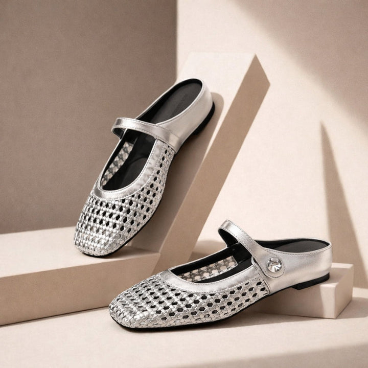 Woven metallic flat mules on a plain background.
