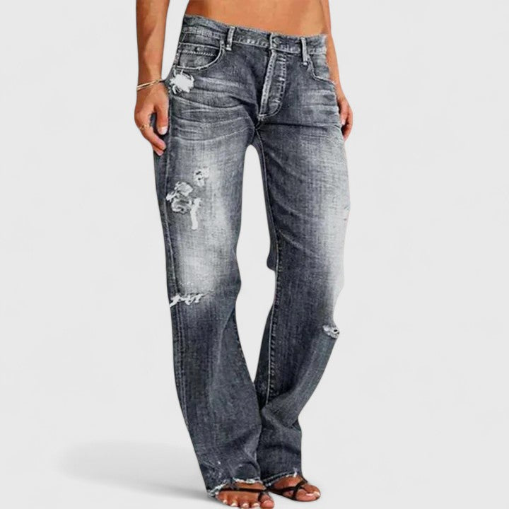 Female model in distressed flare denim jeans with a retro-inspired design.