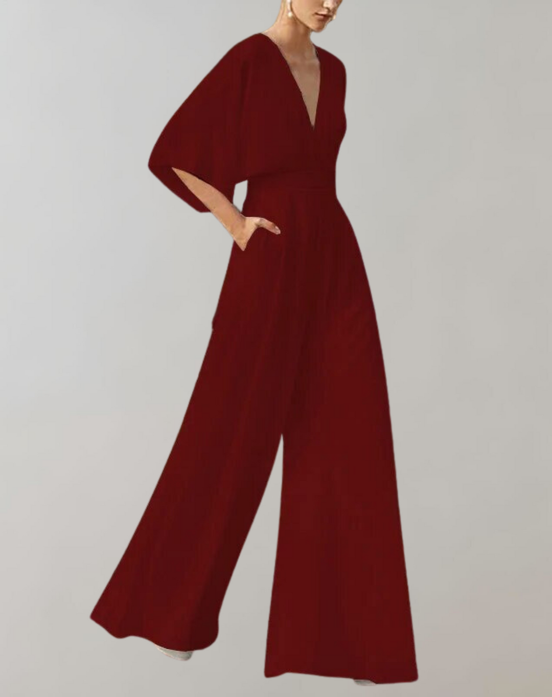 Woman styled in an event ready jumpsuit with loose sleeves on a plain background.