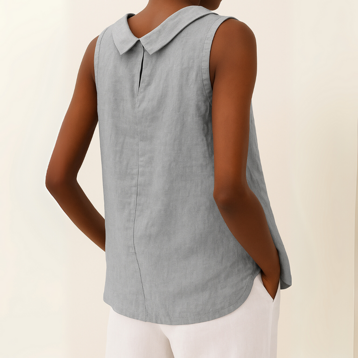  Woman showcasing a sleeveless summer top with a flattering silhouette on a plain background.