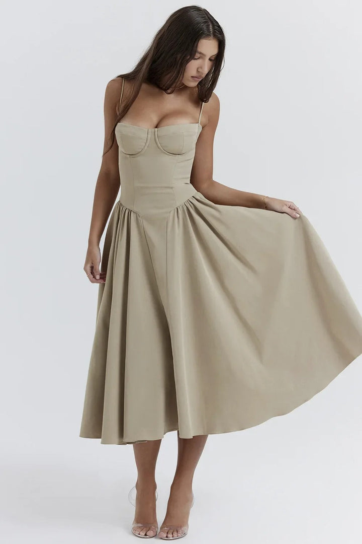Woman standing in a feminine dress with a soft skirt on a plain background.