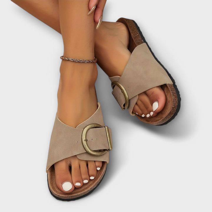 Woman showcasing adjustable strap sandals on a plain background.