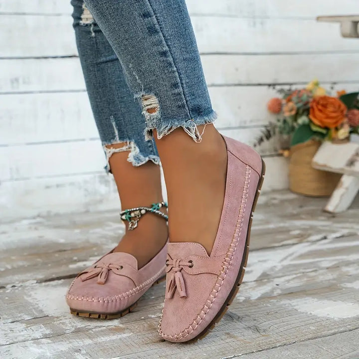 Women’s slip-on flats with classic detailing on a plain background.