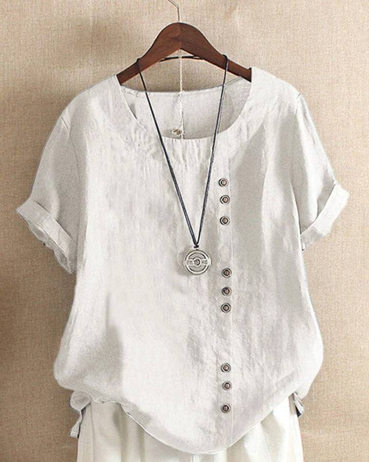  Female modelling a crew neck top with decorative front buttons on a plain background.